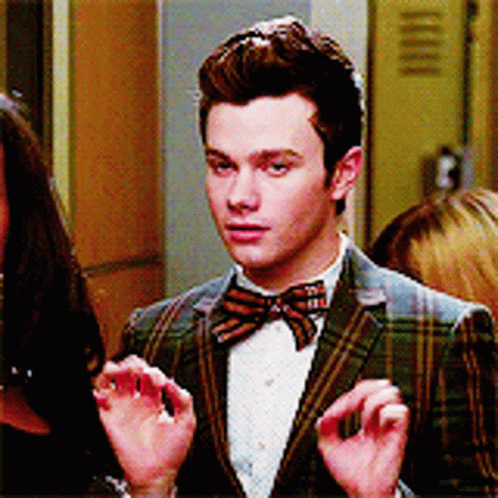 A Man In A Plaid Jacket And Bow Tie Is Talking To A Woman GIF
