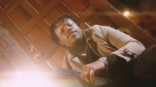 A Man In A Plaid Jacket Is Laying Down In Front Of A Wooden Door . GIF