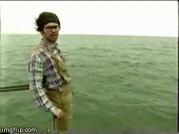 A Man In A Plaid Shirt And Overalls Is Standing In The Water . GIF