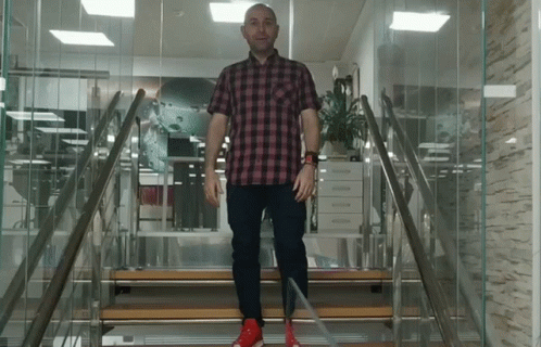 A Man In A Plaid Shirt And Red Shoes Is Walking Up A Set Of Stairs GIF