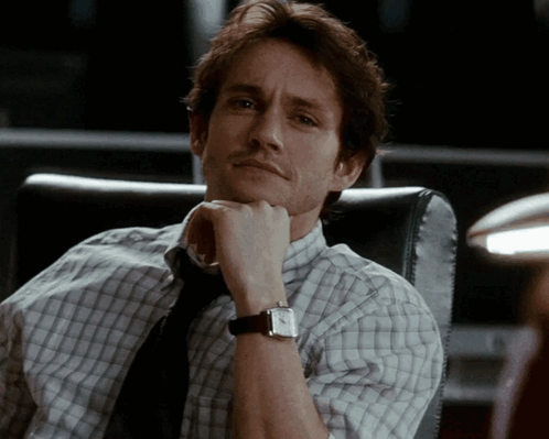 A Man In A Plaid Shirt And Tie Is Wearing A Watch GIF