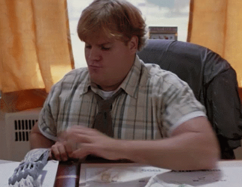 A Man In A Plaid Shirt And Tie Sits At His Desk GIF