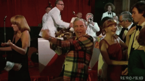 A Man In A Plaid Shirt Is Dancing In Front Of A Band With The Words Retro-Fiend On The Bottom GIF