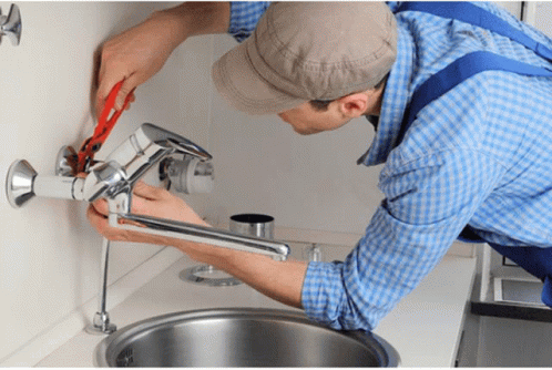 A Man In A Plaid Shirt Is Fixing A Faucet With A Pair Of Pliers GIF