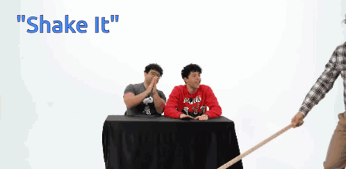 A Man In A Plaid Shirt Is Holding A Cane In Front Of A Chalkboard That Says Shake It GIF