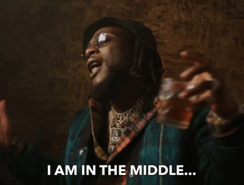 A Man In A Plaid Shirt Is Holding A Glass And Says " I Am In The Middle " GIF