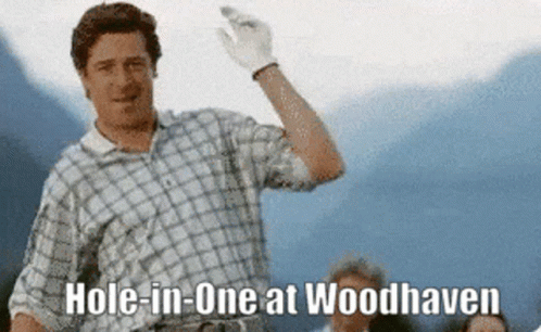 A Man In A Plaid Shirt Is Holding A Golf Club And Says Hole In One At Woodhaven GIF