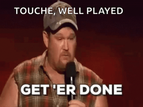 A Man In A Plaid Shirt Is Holding A Microphone And Saying `` Touch , Well Played Get 'Er Done '' . GIF