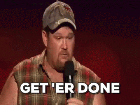 A Man In A Plaid Shirt Is Holding A Microphone And Says `` Get 'Er Done '' . GIF