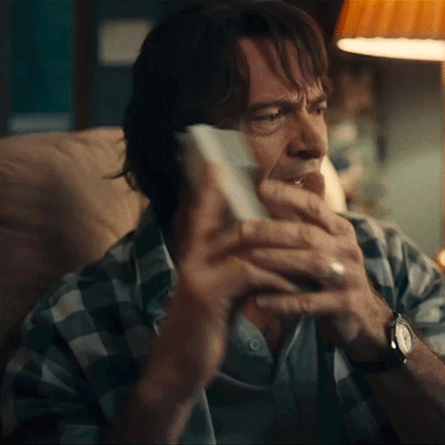 a man in a plaid shirt is holding a piece of paper in his hand