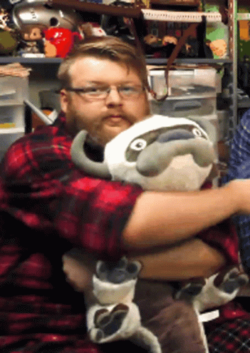 A Man In A Plaid Shirt Is Hugging A Stuffed Animal GIF