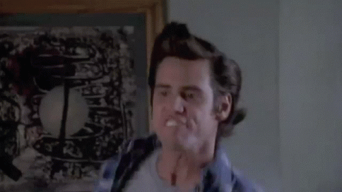 A Man In A Plaid Shirt Is Making A Funny Face In Front Of A Picture . GIF