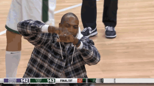 a man in a plaid shirt is making a funny face in front of a scoreboard that says 143 final / ot