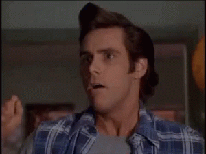 A Man In A Plaid Shirt Is Making A Funny Face While Standing In A Room . GIF
