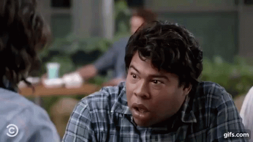 A Man In A Plaid Shirt Is Making A Funny Face While Talking To A Woman . GIF