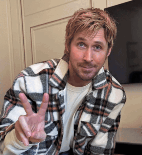 A Man In A Plaid Shirt Is Making A Peace Sign GIF