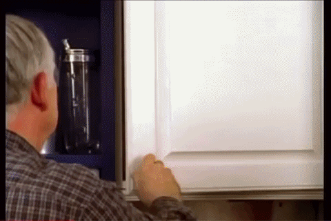 A Man In A Plaid Shirt Is Opening A Cabinet GIF