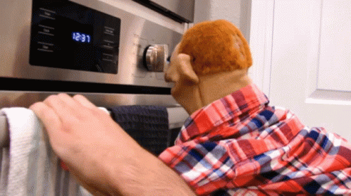 A Man In A Plaid Shirt Is Putting A Towel On A Towel Rack In Front Of An Oven That Says 12:31 GIF