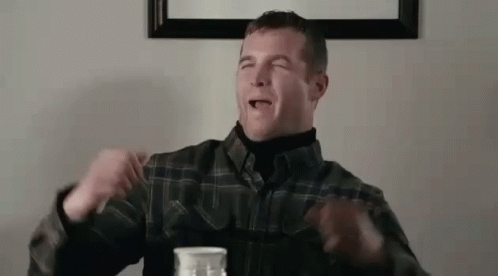 A Man In A Plaid Shirt Is Sitting At A Table With A Bottle Of Milk In Front Of Him . GIF