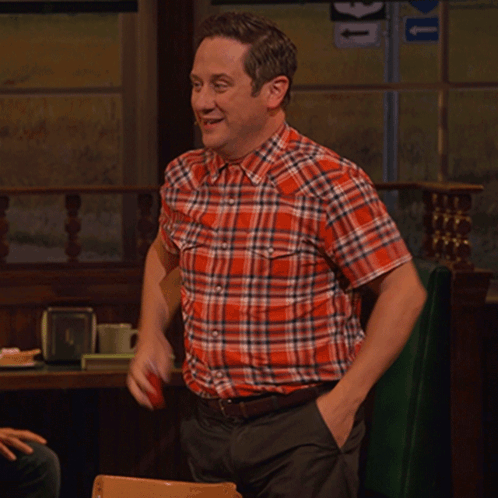 A Man In A Plaid Shirt Is Sitting At A Table With A Sign That Says U On It GIF