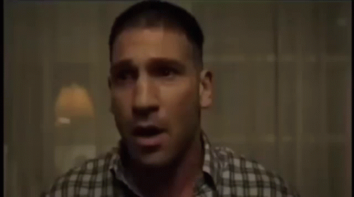 A Man In A Plaid Shirt Is Sitting In A Chair And Crying GIF