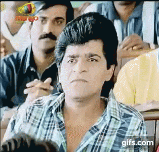 A Man In A Plaid Shirt Is Sitting In Front Of A Group Of People . GIF