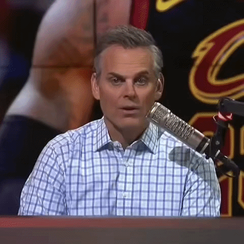 A Man In A Plaid Shirt Is Sitting In Front Of A Microphone And Making A Funny Face . GIF