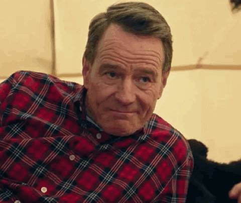 A Man In A Plaid Shirt Is Sitting In Front Of A Tent And Smiling . GIF