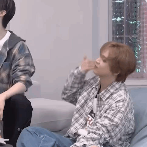 A Man In A Plaid Shirt Is Sitting On A Couch And Making A Funny Face . GIF