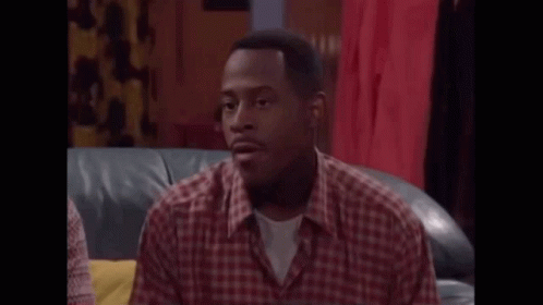 A Man In A Plaid Shirt Is Sitting On A Couch And Talking . GIF