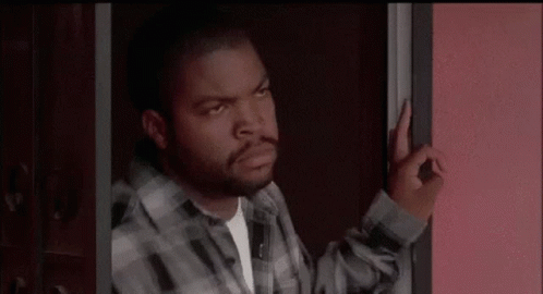 A Man In A Plaid Shirt Is Standing In A Doorway And Making An Okay Sign . GIF