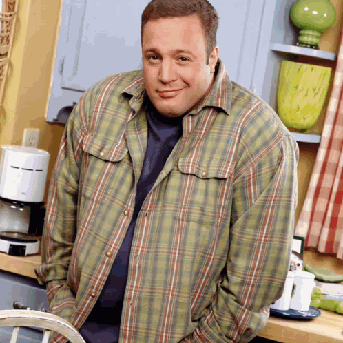 A Man In A Plaid Shirt Is Standing In Front Of A Coffee Maker GIF