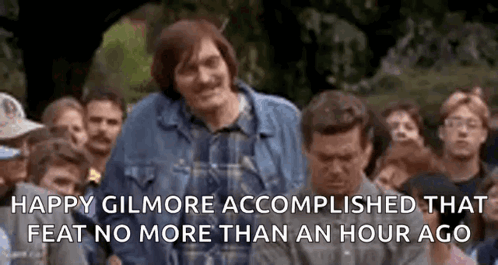 A Man In A Plaid Shirt Is Standing In Front Of A Crowd . GIF