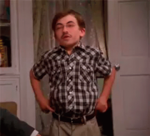 A Man In A Plaid Shirt Is Standing In Front Of A Door With The Word Fashion Written On It . GIF