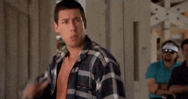 A Man In A Plaid Shirt Is Standing In Front Of A Group Of Men In A Room . GIF