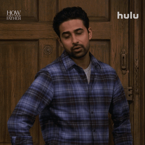 A Man In A Plaid Shirt Is Standing In Front Of A Wooden Door And Says No Big Deal GIF