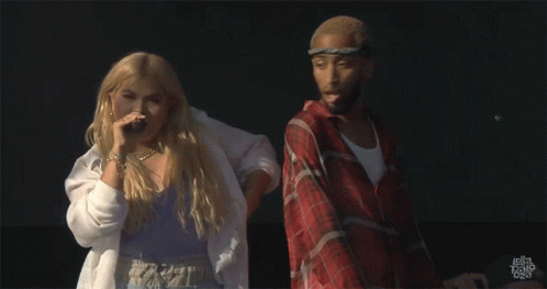 A Man In A Plaid Shirt Is Standing Next To A Woman In A White Shirt That Says Hayley Bravo On The Bottom GIF