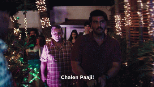 A Man In A Plaid Shirt Is Standing Next To Another Man With The Words Chalen Paaji Written Below Him GIF