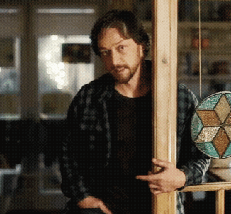 A Man In A Plaid Shirt Leans Against A Wooden Pole GIF