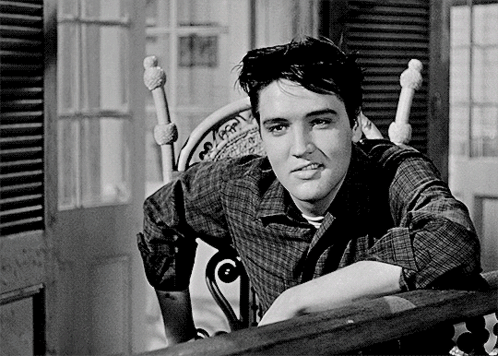 A Man In A Plaid Shirt Leans On A Railing GIF