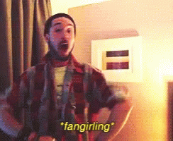 A Man In A Plaid Shirt Says " Fangirling " In A Room GIF