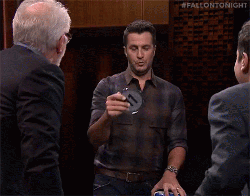 A Man In A Plaid Shirt Says Ruh Roh In Front Of A Group Of Men GIF