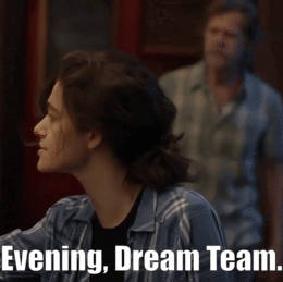 A Man In A Plaid Shirt Stands In A Crowd With The Words Evening Dream Team Written Below Him GIF