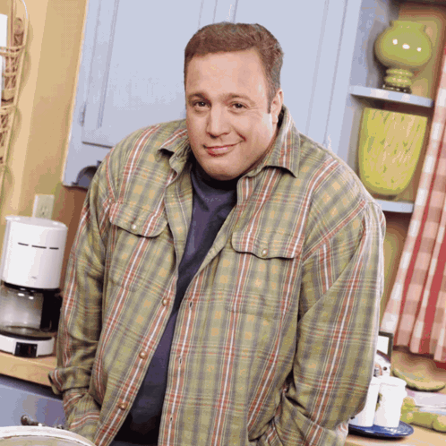 A Man In A Plaid Shirt Stands In Front Of A Coffee Maker GIF