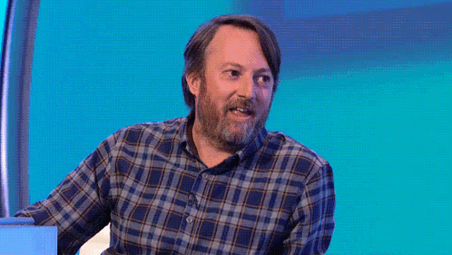 A Man In A Plaid Shirt Stands In Front Of A Purple Background That Says I Am Not Okay GIF