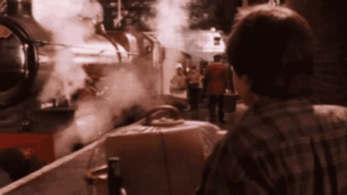 a man in a plaid shirt stands in front of a train that has the number 5 on the front