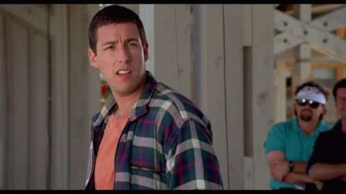 A Man In A Plaid Shirt Stands With His Arms Crossed In Front Of Two Other Men GIF