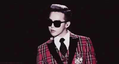 A Man In A Plaid Suit And Sunglasses Is Pointing At Something . GIF