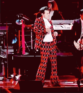 a man in a plaid suit is dancing on a stage