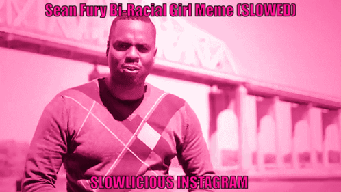 A Man In A Plaid Sweater Stands In Front Of A Pink Background That Says Slowlicious Instagram On It GIF